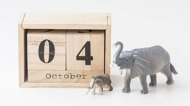 Kostenloses Foto vorderansicht von elefantenfiguren mit holzkalender für tiertag
