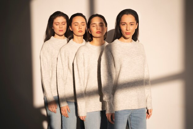 Vorderansicht von Frauen in Pullovern und Jeans, die im Fensterschatten posieren