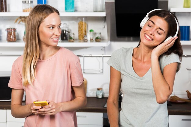 Vorderansicht von Frauen zu Hause, die Musik über Kopfhörer hören