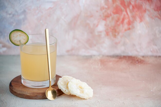 Vorderansicht von frischem Saft und goldenem Löffel auf kleinem Holzbrett auf pastellfarbenem Hintergrund