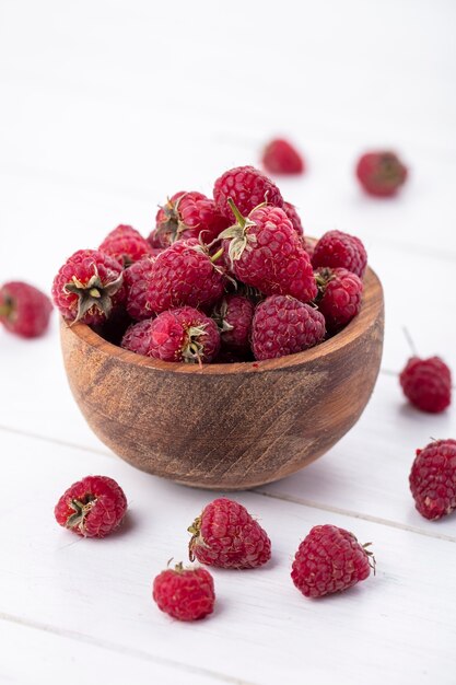 Vorderansicht von Himbeeren in einer Holzschale auf einer weißen Oberfläche