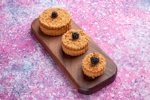 Vorderansicht von kleinen köstlichen Kuchen rund gebildet auf der rosa Oberfläche