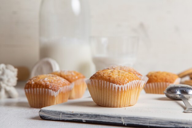 Vorderansicht von kleinen leckeren Kuchen mit Zuckerpulver auf dem weißen Schreibtisch