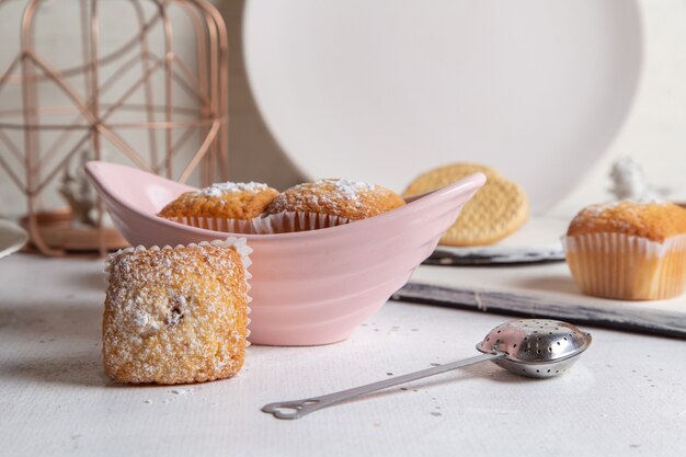 Vorderansicht von kleinen leckeren Kuchen mit Zuckerpulver auf der weißen Oberfläche