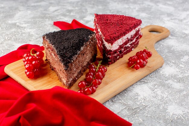 Vorderansicht von köstlichen Kuchenscheiben mit Sahneschokolade und Früchten mit rotem Gewebe