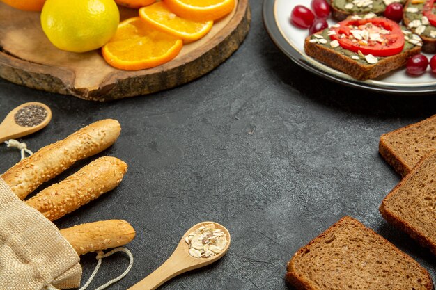 Vorderansicht von leckeren Avocado-Sandwiches mit frischen Orangen auf grauer Oberfläche