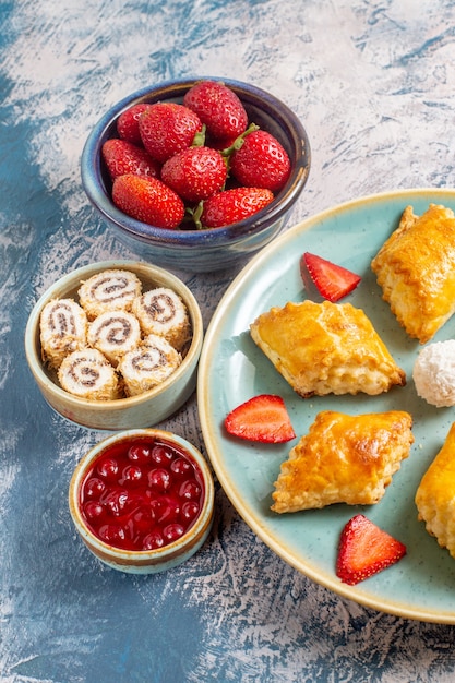 Vorderansicht von leckeren süßen Kuchen mit Früchten und Nüssen auf blauer Oberfläche