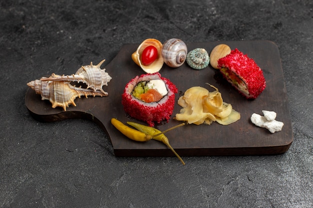 Vorderansicht von leckeren Sushi-Mahlzeit geschnittenen Fischröllchen mit Muscheln an der grauen Wand