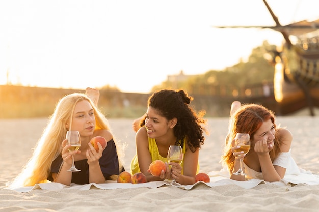 Vorderansicht von Mädchen, die Wein am Strand trinken