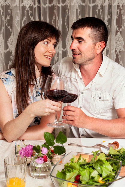 Vorderansicht von Mann und Frau am Esstisch mit Wein
