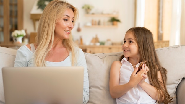Vorderansicht von Mutter und Tochter zu Hause mit Laptop und Smartphone