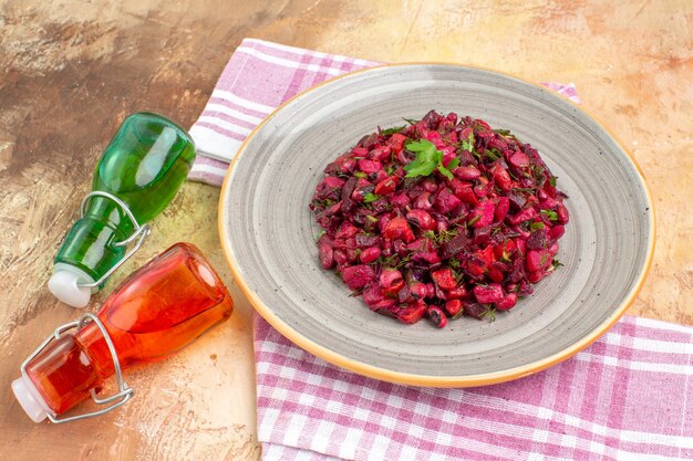 Vorderansicht von oben auf schön aussehende Ölflaschen und lila gestreiftes Handtuch und leckeren Salat