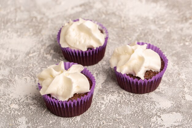 Vorderansicht von Schokoladenbrownies mit Creme auf der weißen Oberfläche