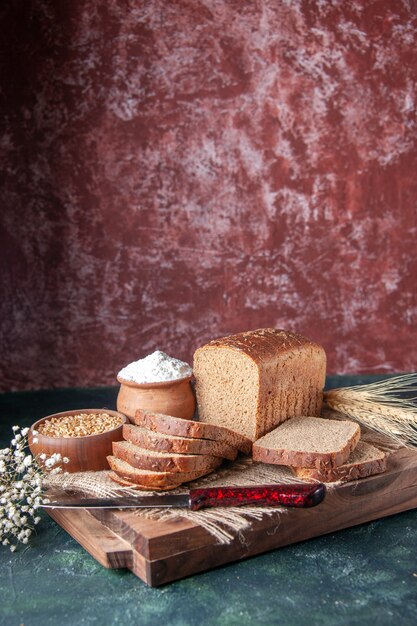 Vorderansicht von Schwarzbrotscheiben auf nackten Handtuchspitzen blühen auf Schneidebrettern auf gemischtem Hintergrund