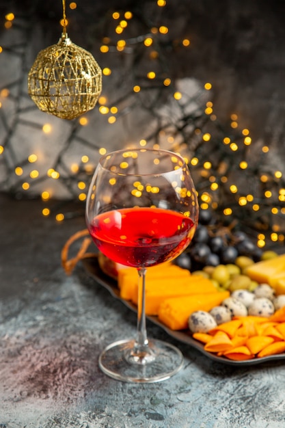 Vorderansicht von trockenem Rotwein in einem Glas neben einem Snack auf grauem Hintergrund