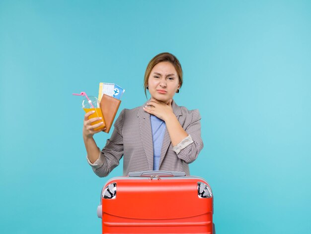 Vorderansicht weiblich im Urlaub, der frisches Getränk und Tickets auf Seeurlaubsreise des blauen Hintergrunds hält