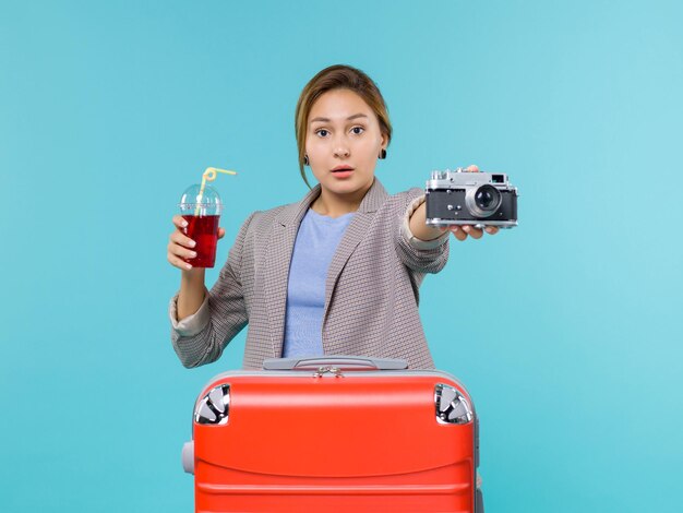 Vorderansicht weiblich im Urlaub, der Saft mit Kamera auf hellblauem Hintergrundreise-Reise-Urlaubsreise-Wasserflugzeug hält