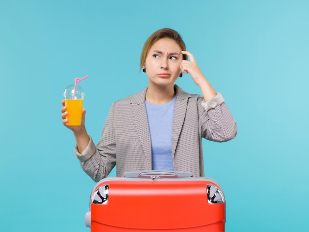 Vorderansicht weiblich im Urlaub mit großer roter Tasche, die frischen Saft auf blauem Hintergrund-Seeferienflugreise-Reisereise hält