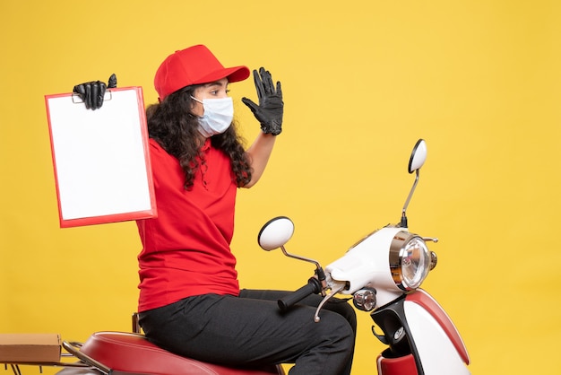 Vorderansicht weiblicher Kurier in Maske mit Dateinotiz auf gelbem Hintergrund Covid-Job Uniform Worker Service Delivery