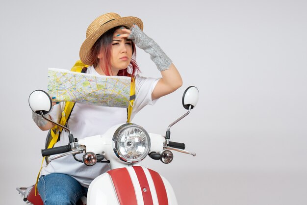 Vorderansicht weiblicher Tourist, der auf Motorrad mit weißer Wand der Karte sitzt