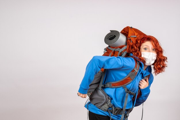 Vorderansicht weiblicher Tourist, der in Bergtour in Maske mit Rucksack geht