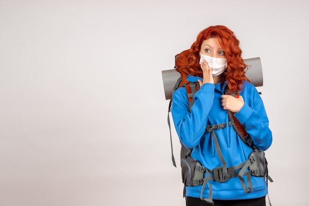 Kostenloses Foto vorderansicht weiblicher tourist, der in bergtour in maske mit rucksack geht