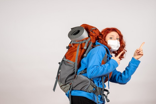 Vorderansicht weiblicher Tourist, der in Bergtour in Maske mit Rucksack geht