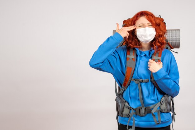 Vorderansicht weiblicher Tourist, der in Bergtour in Maske mit Rucksack geht