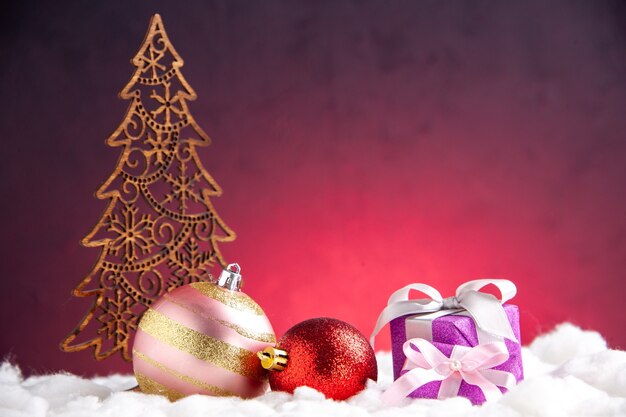 Vorderansicht Weihnachtsbaumkugeln Weihnachtsdekoration kleine Geschenke auf rotem Hintergrund