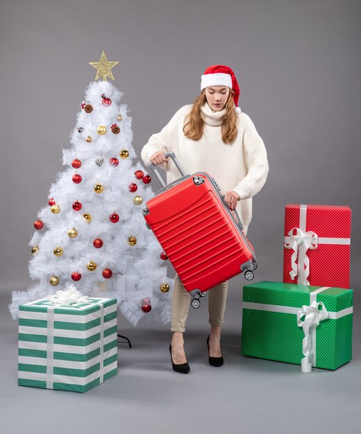 Vorderansicht-Weihnachtsfrau, die Weihnachtsmütze trägt, die nahe Weihnachtsbaum bleibt