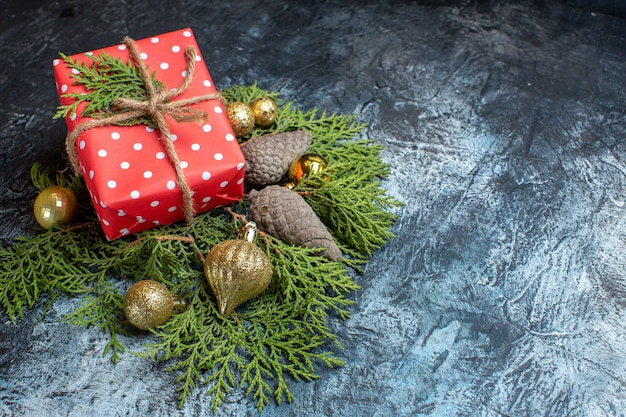 Kostenloses Foto vorderansicht weihnachtsgeschenk mit grünem zweig und spielzeug auf heller oberfläche