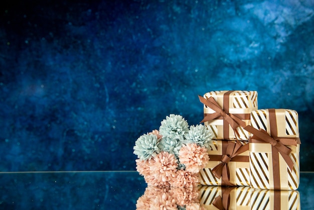 Vorderansicht Weihnachtsgeschenke Blumen reflektiert auf Spiegel auf dunkelblauem Hintergrund mit Kopie Platz
