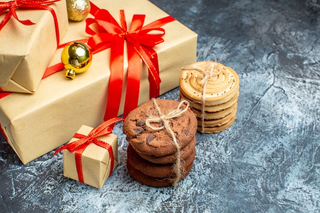 Vorderansicht Weihnachtsgeschenke mit süßen Keksen auf dem hell-dunkel Urlaub Foto Geschenk Weihnachtsfarbe Neujahr