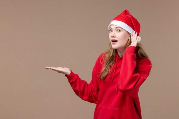 Vorderansicht-Weihnachtsmädchen, das auf braunem Hintergrund Neujahrs-Weihnachtsfeiertag hört