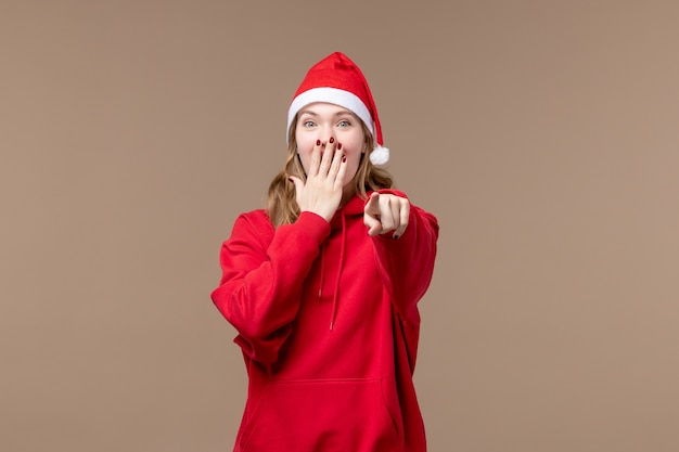 Vorderansicht-Weihnachtsmädchen, das auf braunen Hintergrundfeiertagen Neujahrsweihnachten lacht