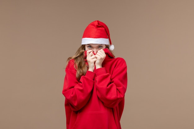 Vorderansicht-Weihnachtsmädchen mit schüchternem Gesicht auf braunem Hintergrundfrauenfeiertagsweihnachten