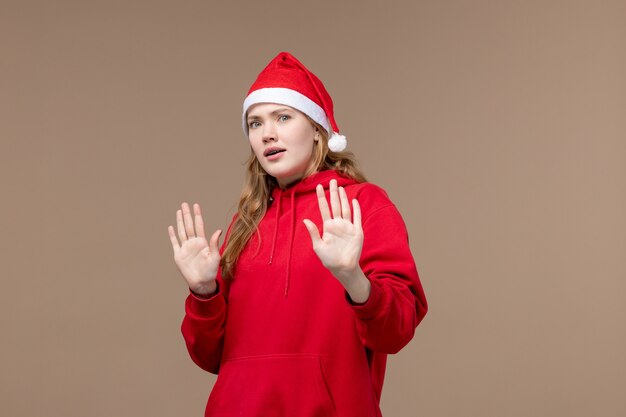 Vorderansicht Weihnachtsmädchen mit verwirrtem Gesicht auf braunem Hintergrundfeiertagsweihnachtsgefühl