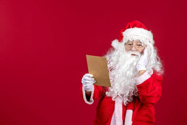 Vorderansicht Weihnachtsmann, der Brief vom Kind auf rotem Gefühl liest, präsentiert Weihnachtsfeiertag