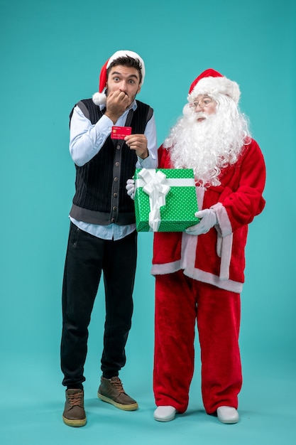 Vorderansicht weihnachtsmann, der geschenk mit jungem mann hält
