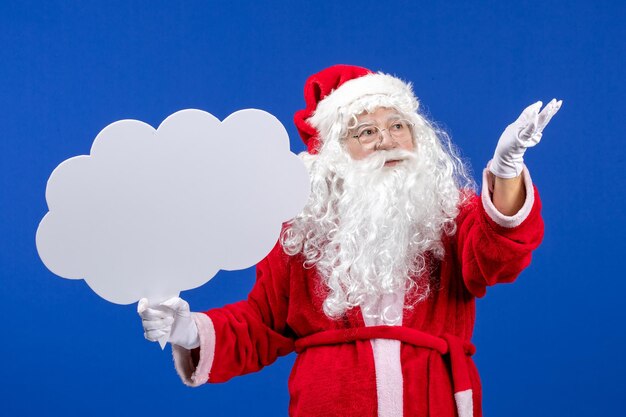 Vorderansicht weihnachtsmann hält großes wolkenförmiges zeichen auf der blauen schneefarbe weihnachten