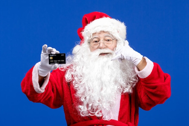 Vorderansicht weihnachtsmann im roten anzug mit schwarzer bankkarte auf dem blauen urlaubsgeschenk weihnachten