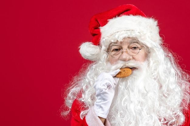 Kostenloses Foto vorderansicht weihnachtsmann isst kekse und trinkt milch