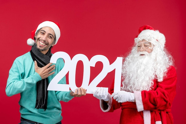 Vorderansicht Weihnachtsmann mit jungem Mann, der auf roten Neujahrsweihnachtsfeiertagsgefühlen schreibt