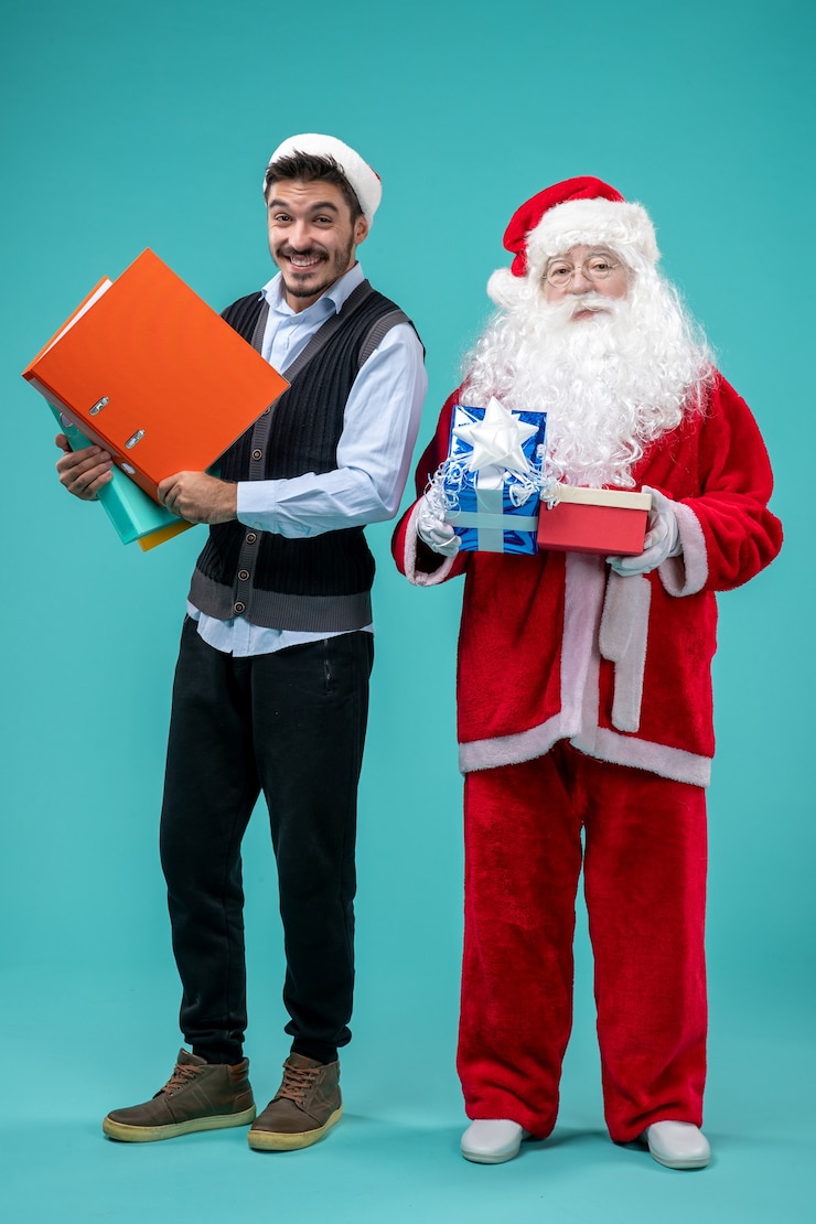 Kostenlose Foto vorderansicht weihnachtsmann mit jungem mann und geschenken auf blauem schreibtisch