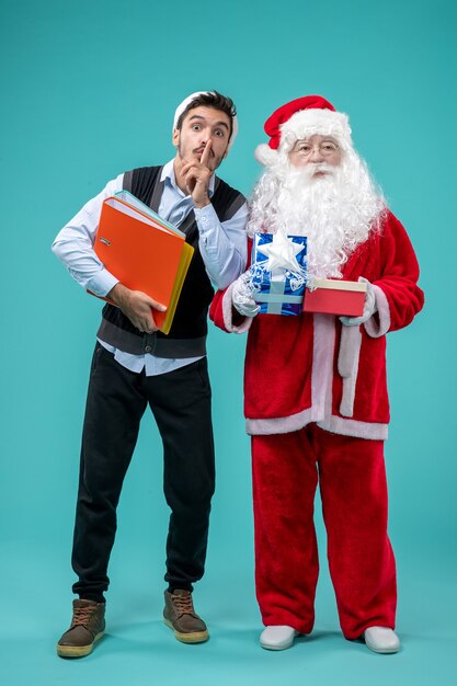 Vorderansicht Weihnachtsmann mit jungem Mann und präsentiert auf dem blauen Hintergrund