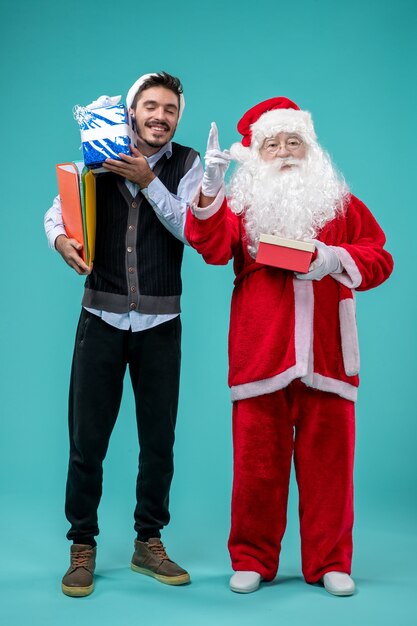 Vorderansicht Weihnachtsmann mit jungem Mann und präsentiert auf dem blauen Hintergrund