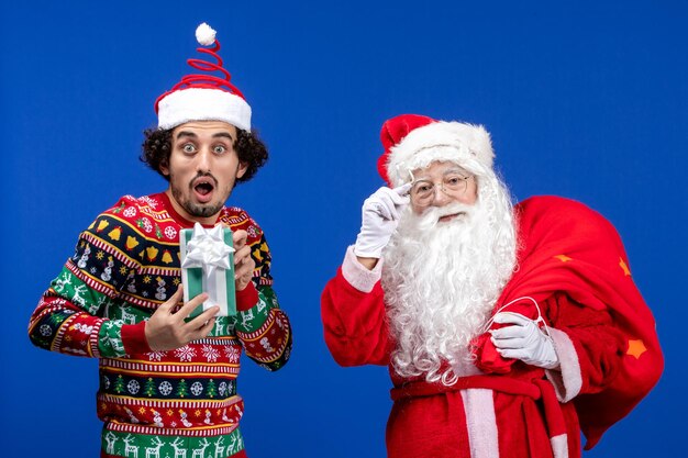 Vorderansicht weihnachtsmann mit jungem mann und tragetasche auf blauen emotionen weihnachtsfeiertagsfarben