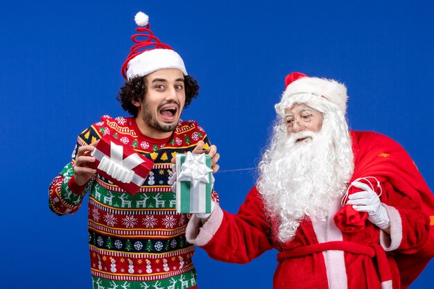 Vorderansicht Weihnachtsmann mit jungen männlichen Haltegeschenken