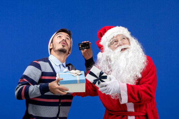 Vorderansicht Weihnachtsmann mit jungen männlichen Haltegeschenken