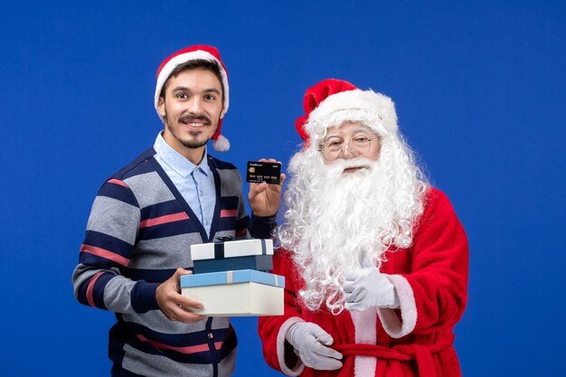 Vorderansicht Weihnachtsmann mit jungen männlichen Haltegeschenken